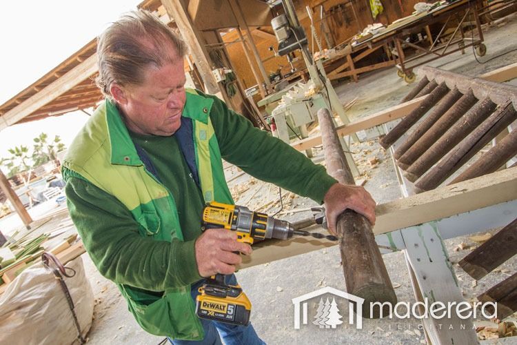 Un hombre está usando un taladro para hacer un agujero en un trozo de madera.