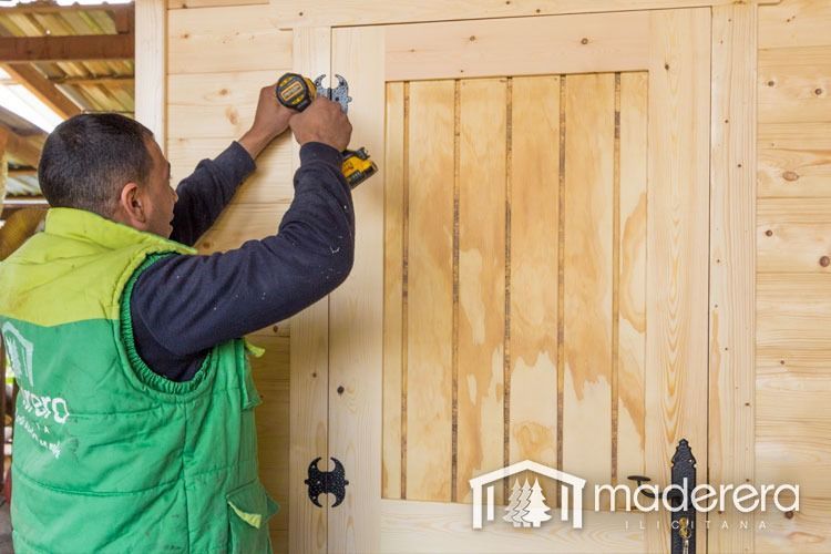 Un hombre está midiendo una puerta de madera con una cinta métrica.