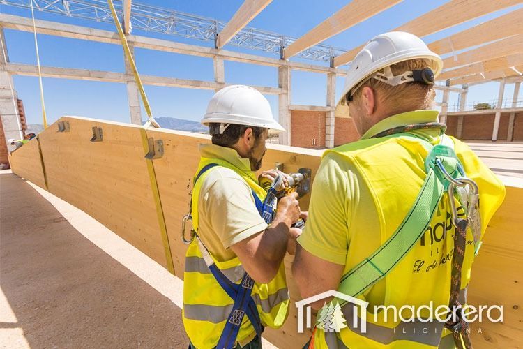 Dos obreros de la construcción trabajan en una estructura de madera.