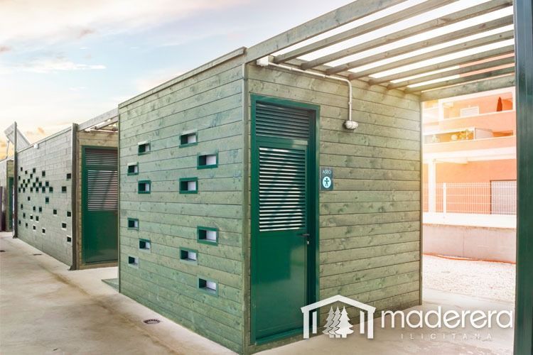 Un edificio de madera con una puerta verde y una pérgola.