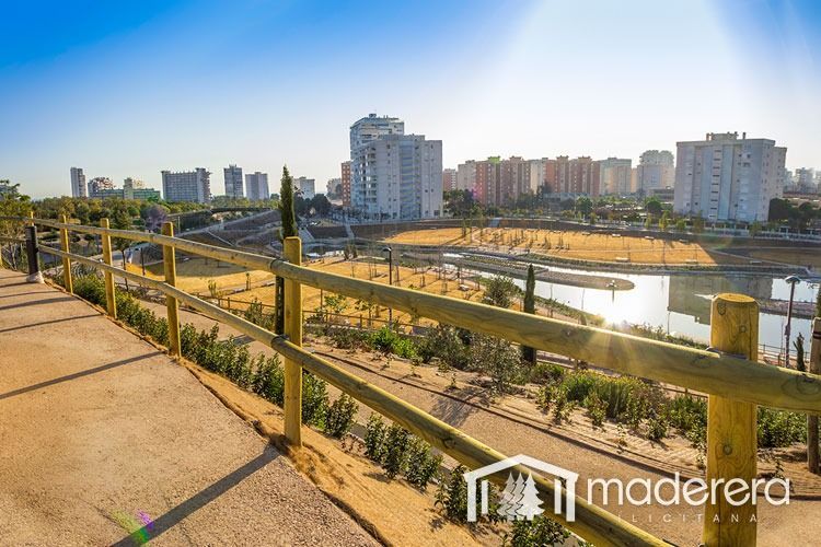 Una valla de madera rodea un río con una ciudad al fondo.