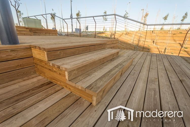 Una terraza de madera con escaleras y barandilla.