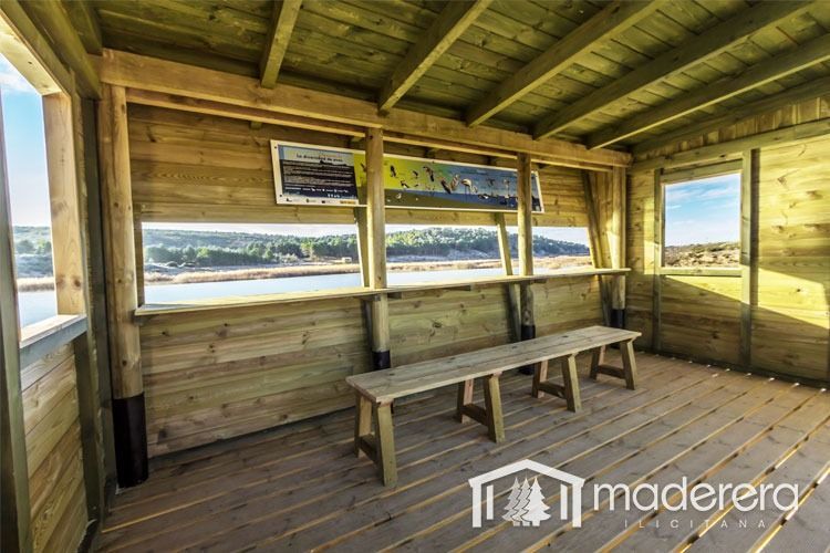 Un edificio de madera con un banco y ventanas que dan a un cuerpo de agua.