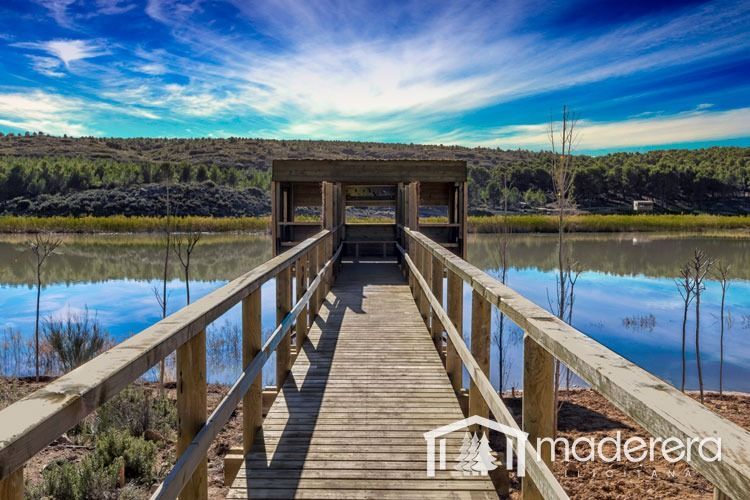Una pasarela de madera que conduce a un refugio con vista a un lago.