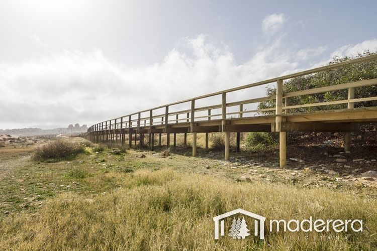 Un puente de madera cruza un campo de hierba.