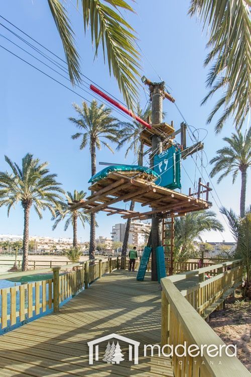 Una pasarela de madera con un circuito de cuerdas al fondo