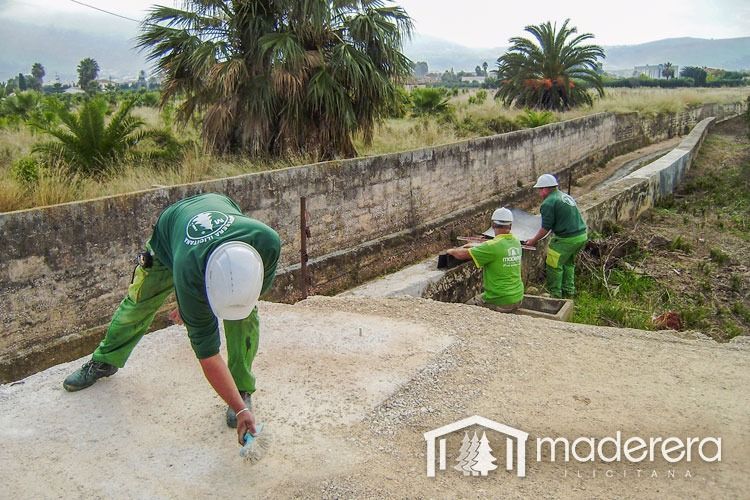Un grupo de hombres está trabajando en un muro de hormigón.
