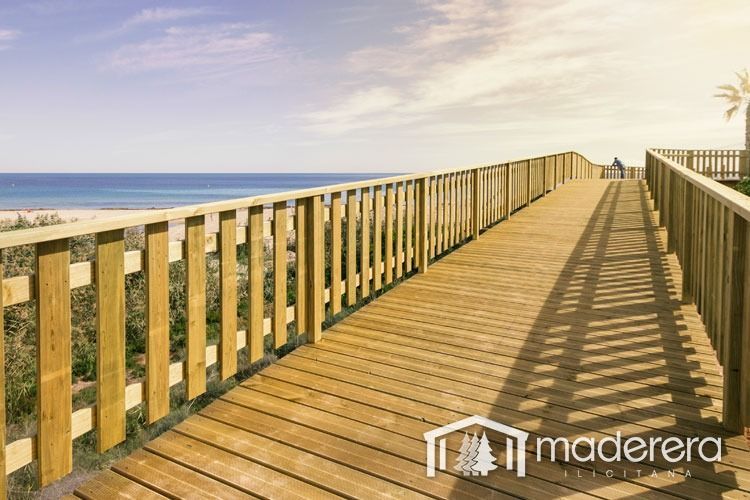 Una pasarela de madera que conduce al océano con una barandilla de madera.