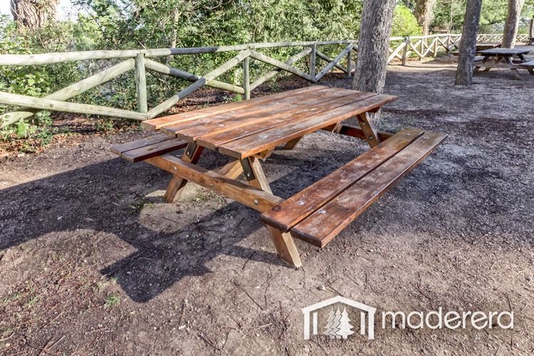 Una mesa de picnic de madera con bancos en un parque.