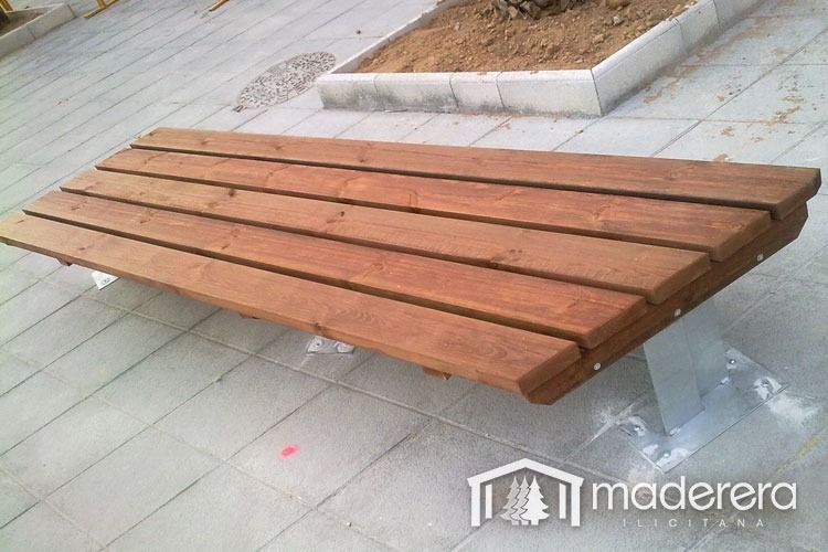 Un banco de madera hecho por maderera se encuentra en una acera