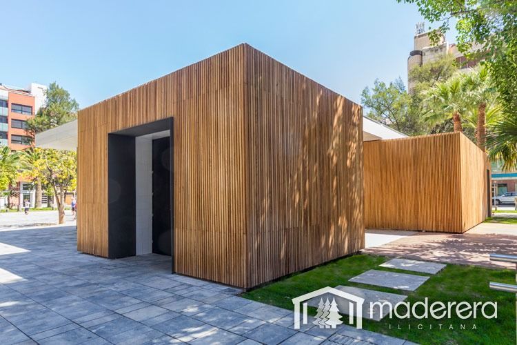 Un edificio de madera con una puerta en medio de un parque.