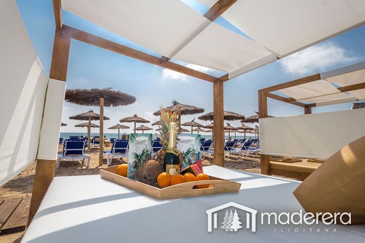 Una bandeja de fruta reposa sobre una cama bajo un dosel en la playa.