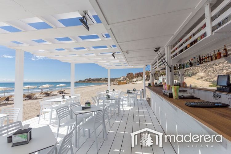 Un restaurante con mesas y sillas y un bar en la playa.