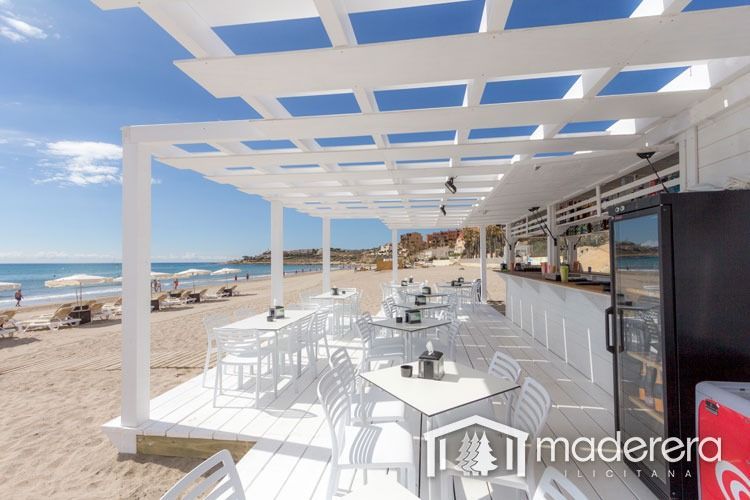 Una hielera de Coca Cola se encuentra frente a un restaurante en la playa.