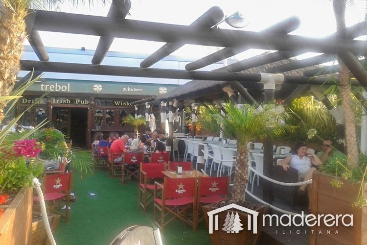 Un grupo de personas están sentadas en mesas afuera de un restaurante llamado maderara