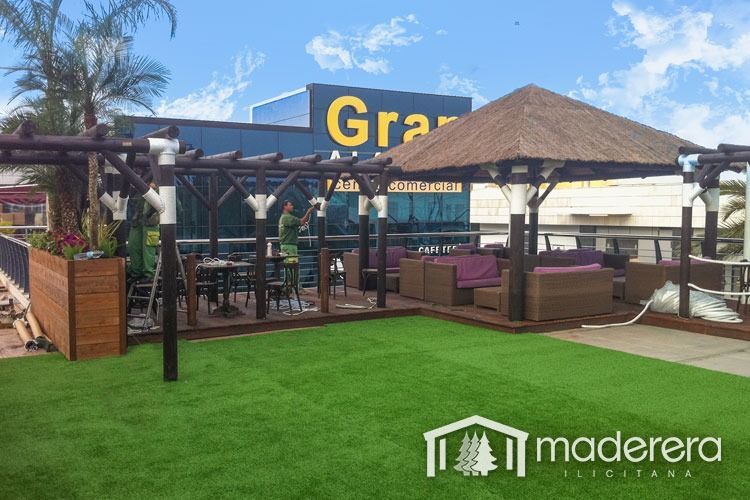 Un mirador se encuentra sobre un exuberante césped verde frente a un edificio.