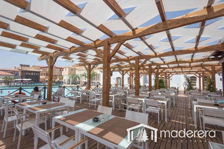 Un restaurante con mesas y sillas bajo un toldo que dice maderera