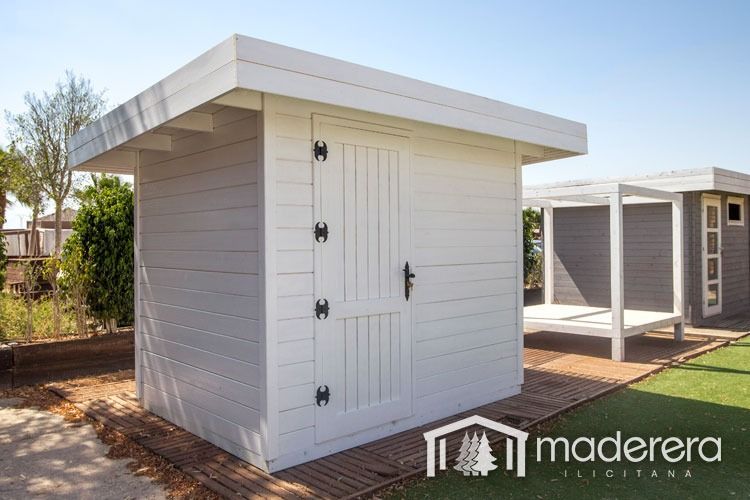 Un cobertizo de madera blanca está situado encima de un camino de entrada de ladrillos.