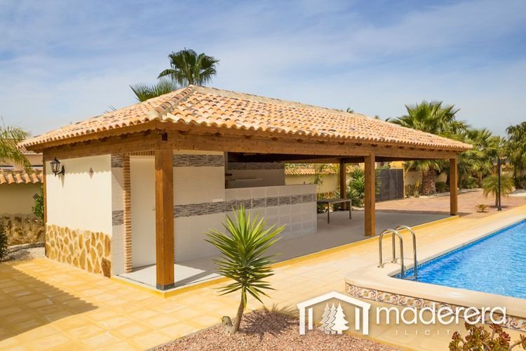 Un pabellón de madera con techo de tejas junto a una piscina.