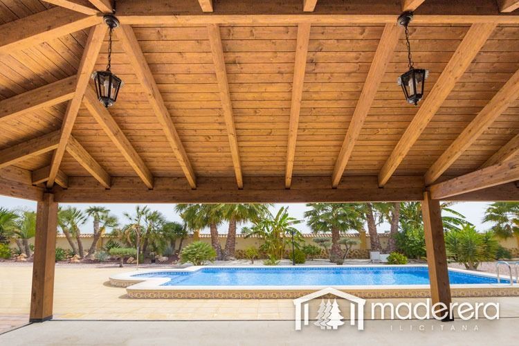 Un cenador de madera con una piscina al fondo.