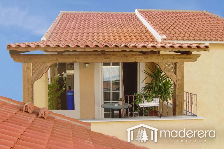 Una casa amarilla con techo de tejas rojas y un balcón