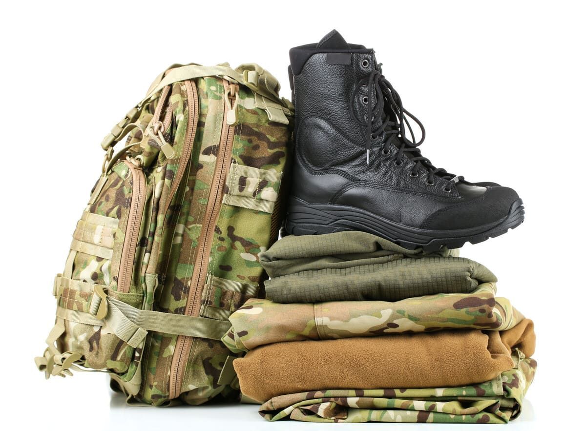 Una pila de ropa militar, una mochila y un par de botas.