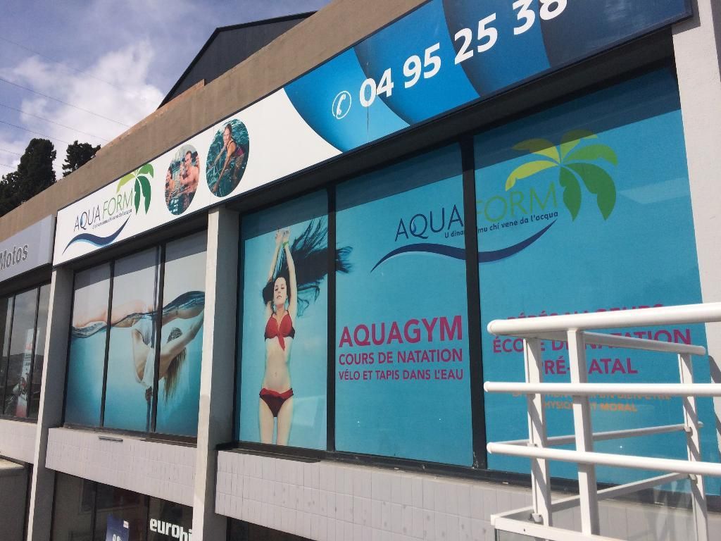 Façade du centre Aquagym, graphisme en vitrine montrant une femme en bikini et un numéro de téléphone.