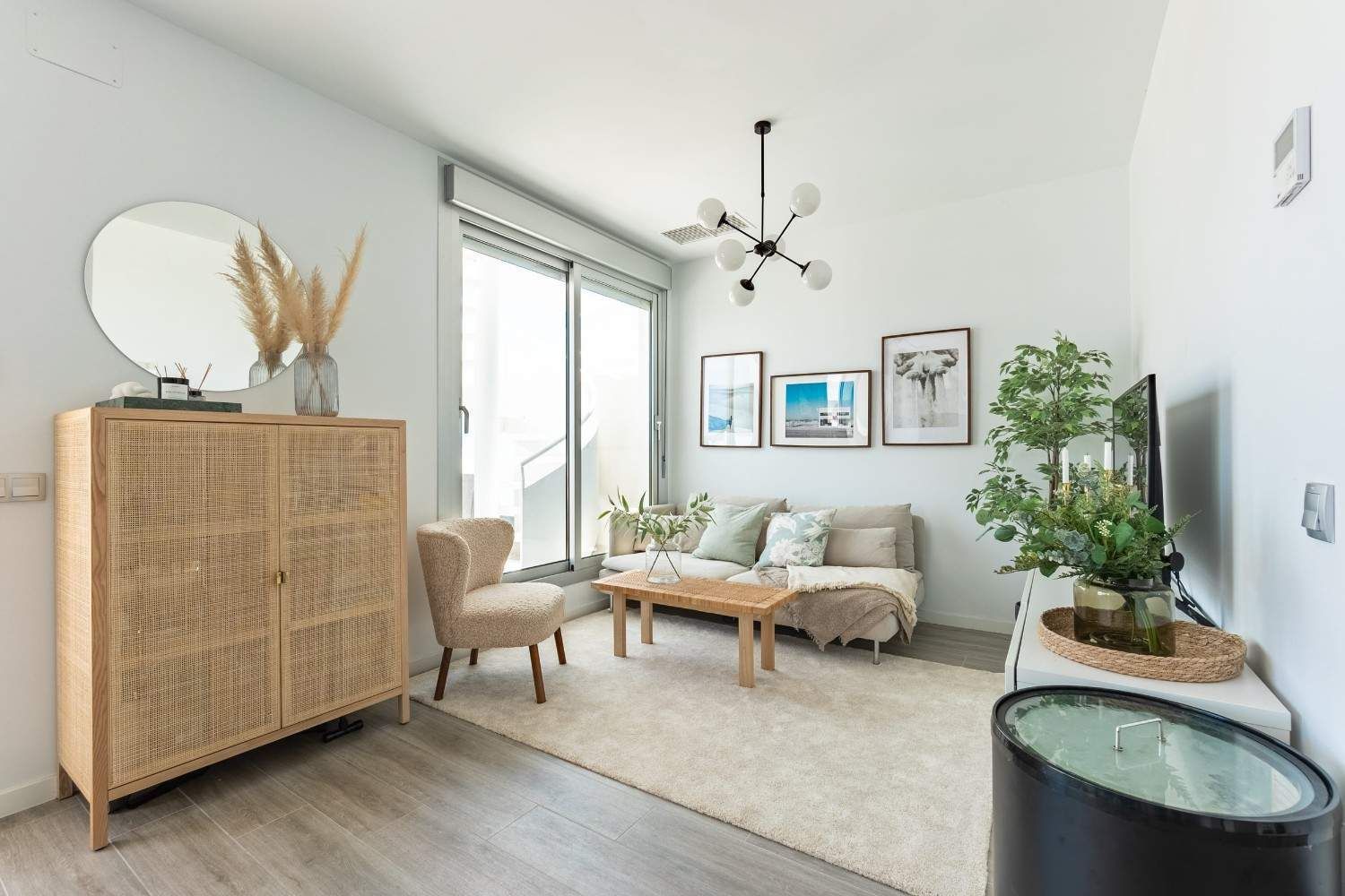 Un salón luminoso y minimalista con un mueble de ratán, un sillón beige, un sofá, una mesa de centro.