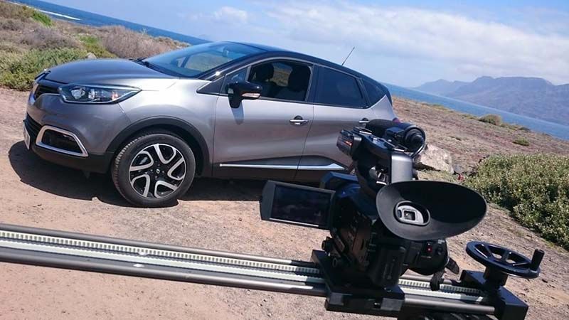 Un coche está aparcado en una pista al lado de una cámara.