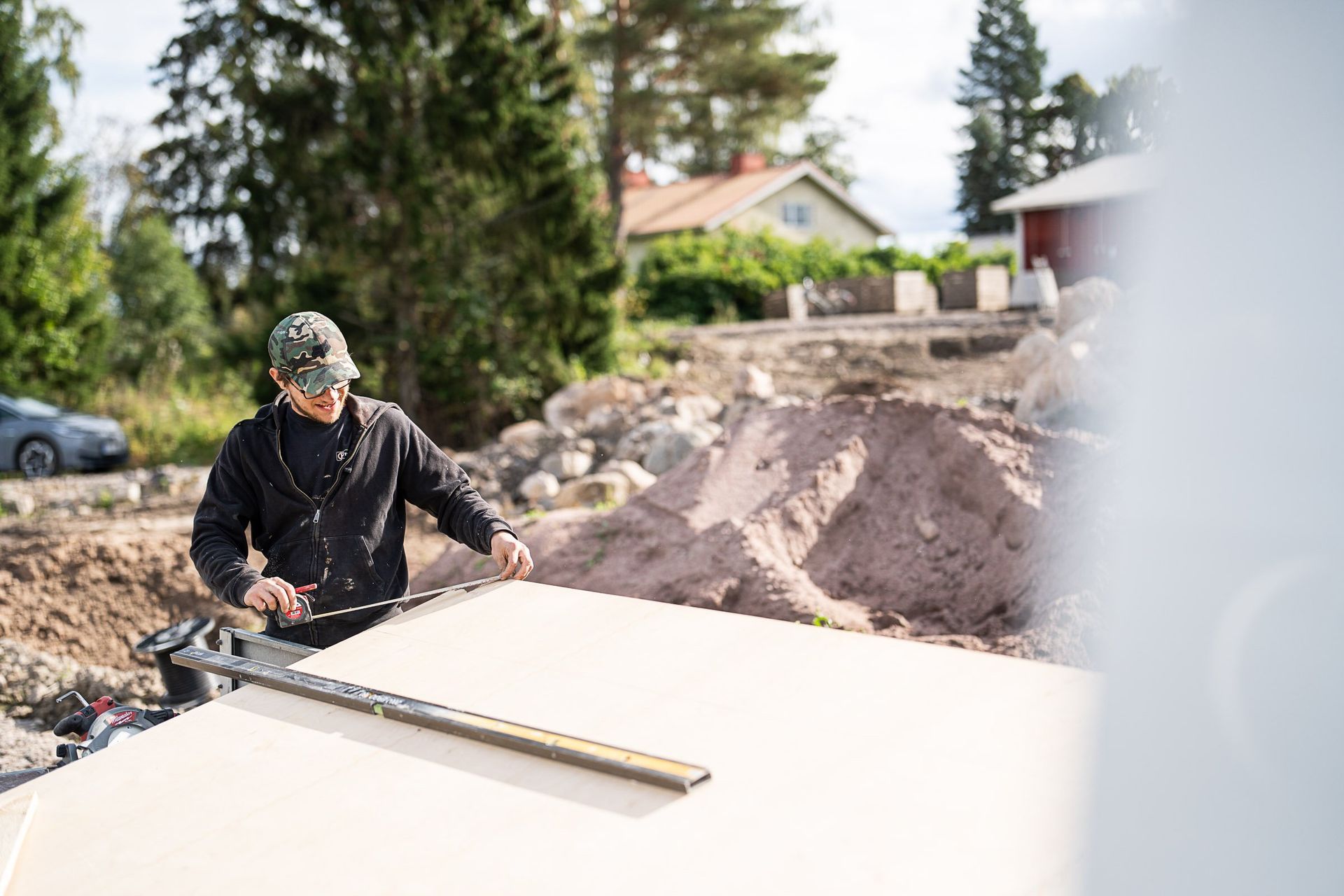Työntekijä tasoittaa betonilaattaa ulkona pitkällä tasoituslaudalla.