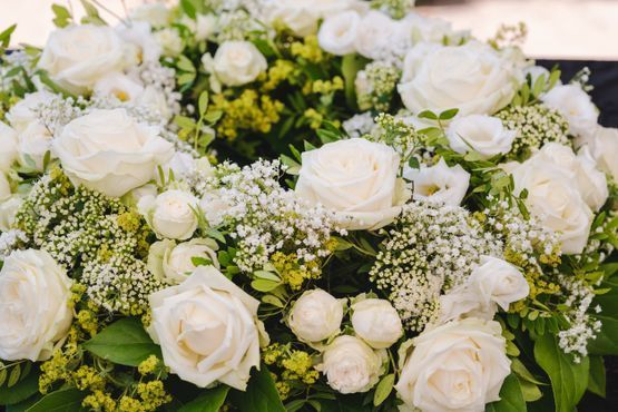 Un primer plano de una corona de rosas blancas y flores de aliento.