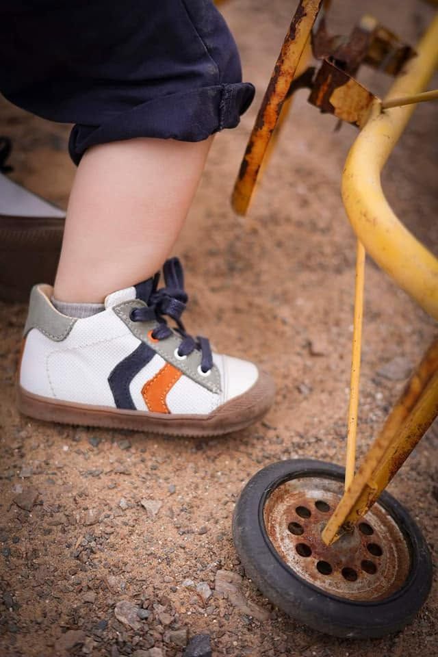 Basket d'enfant sur le sol sablonneux à côté d'une roue de chariot en métal jaune
