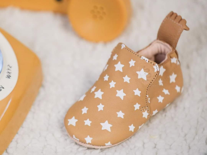 Chausson marron à étoiles blanches sur une douce couverture blanche, avec un jouet jaune à proximité