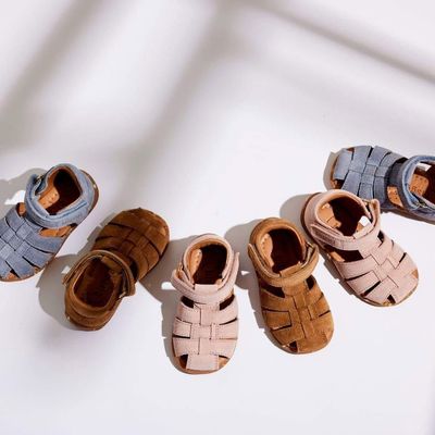 Six petits chaussons de bébé tressés, de couleur bleue, marron, beige et marron clair, disposés en rangée sur une surface blanche.