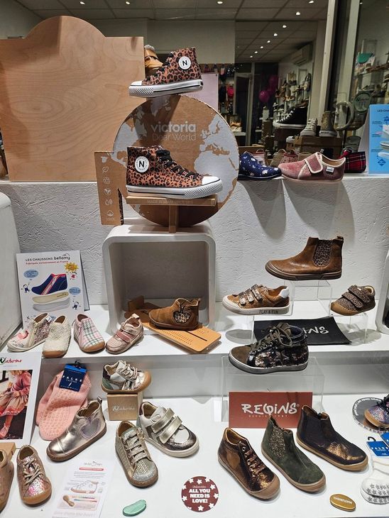 Présentation de chaussures colorées dans un magasin, disposées sur des marches et des étagères avec un centre de table en miroir