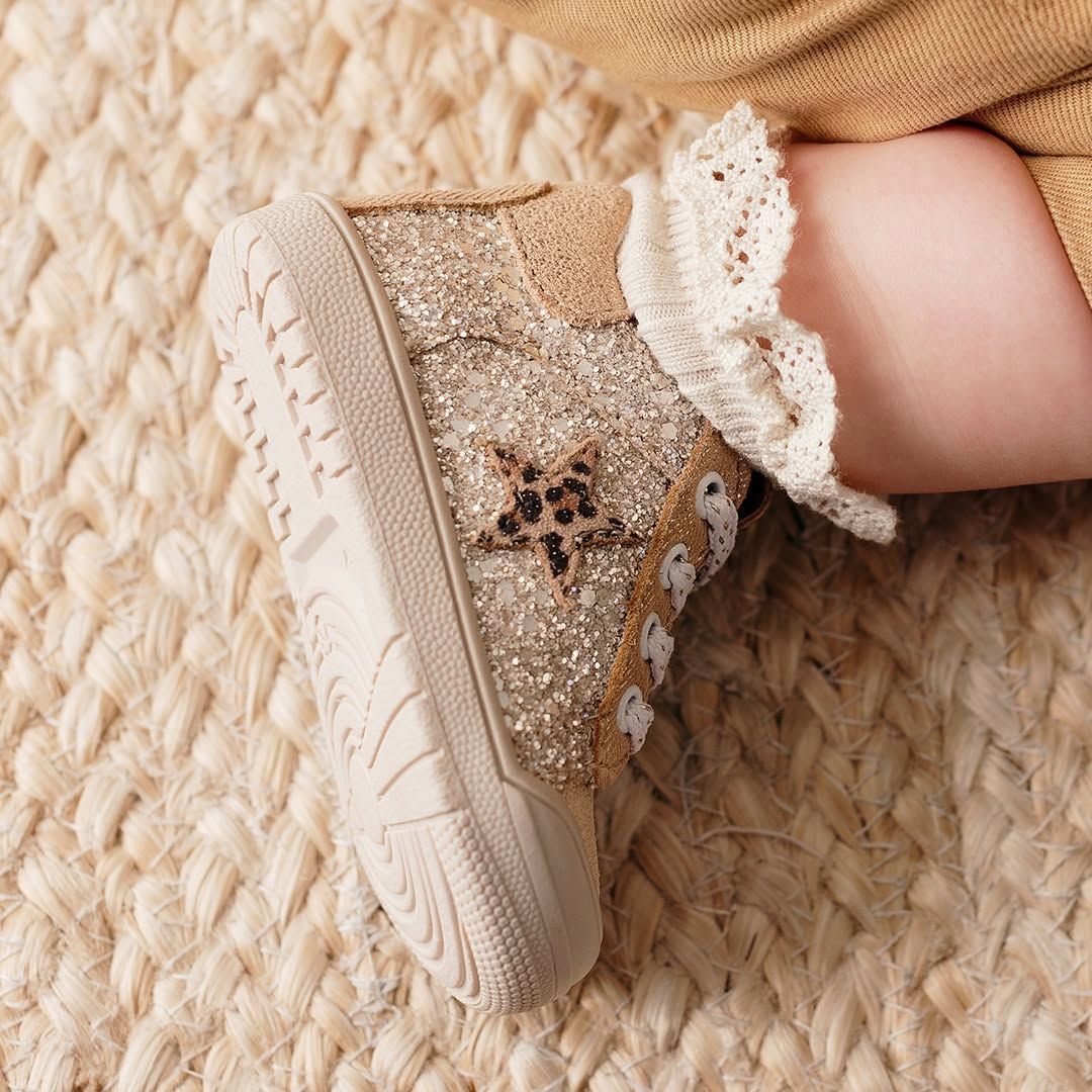 Baskets beiges pailletées pour tout-petits avec bordure en dentelle sur une couverture tissée