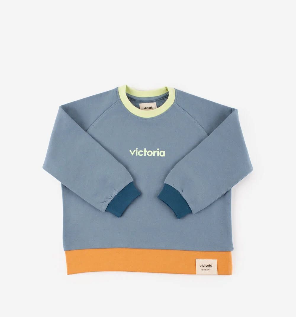 Pull bleu pour enfant avec col jaune et ourlet orange, portant l'inscription Victoria
