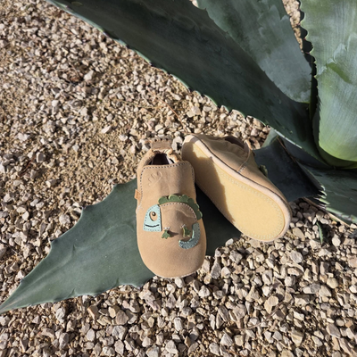 Chaussures beiges à enfiler sur du gravier à côté de feuilles d'agave vertes