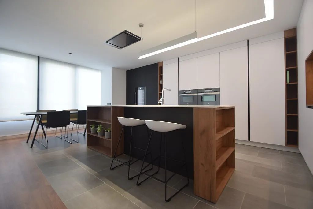 Una cocina con una gran isla y taburetes en ella.
