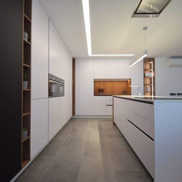 Una cocina con gabinetes blancos y una isla grande.