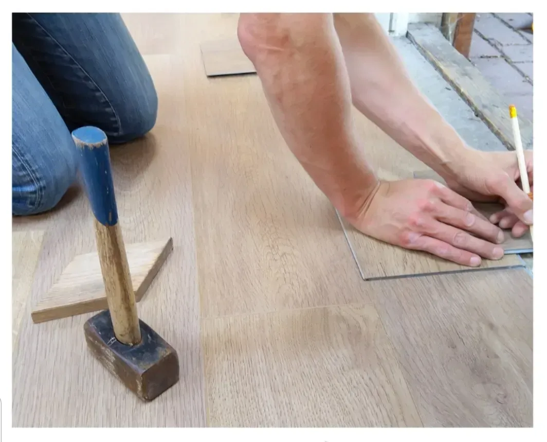 Una persona está midiendo un trozo de madera al lado de un martillo.