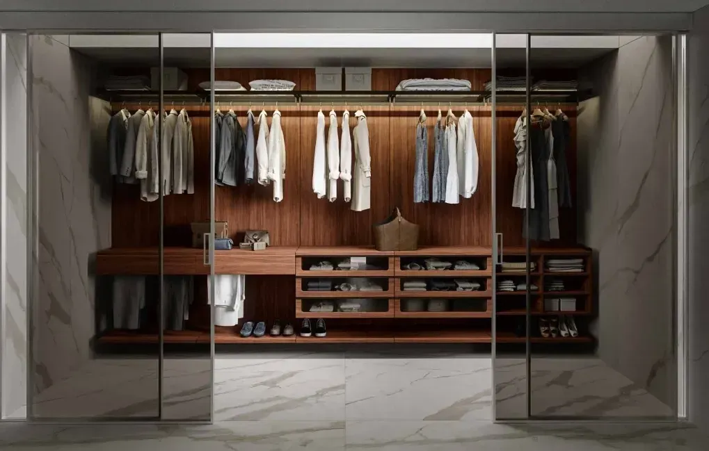 Un vestidor con puertas corredizas de vidrio y estantes de madera.
