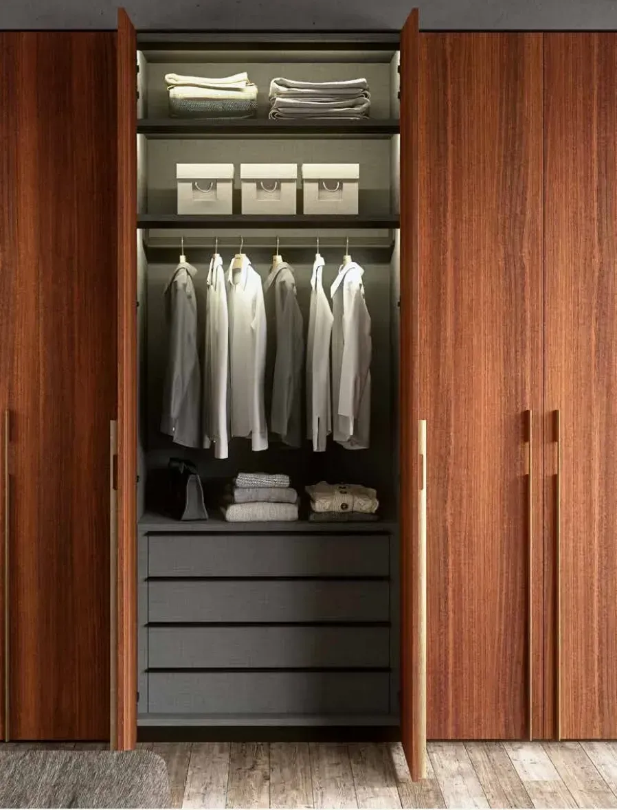 Un armario con puertas de madera y cajones llenos de ropa y cajas.