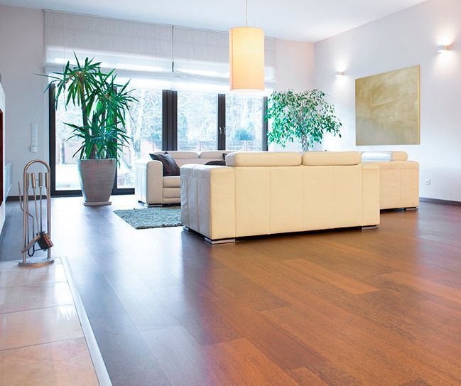 Una sala de estar con pisos de madera y muebles blancos.