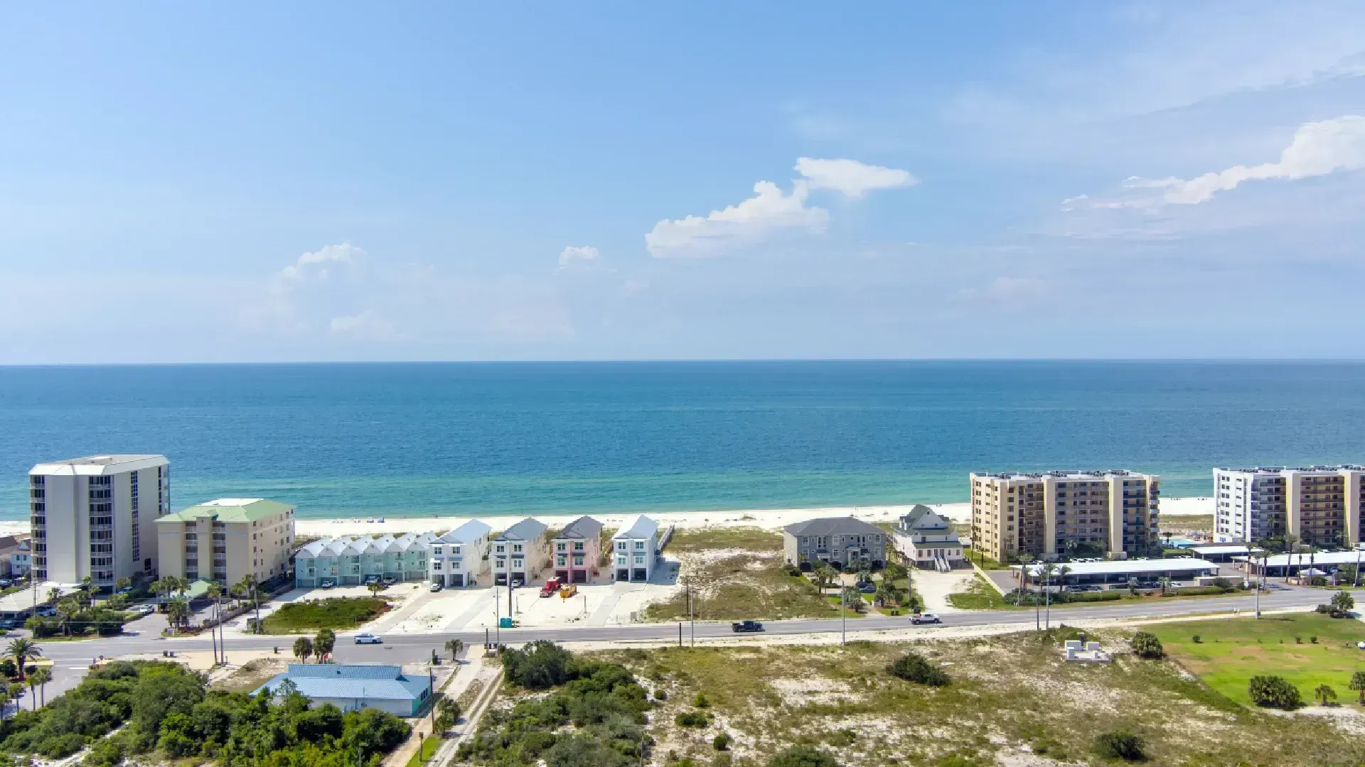 Beachfront buildings and ocean under a blue sky.