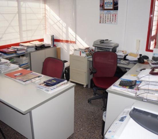 Una oficina con dos escritorios y dos sillas y un calendario en la pared.