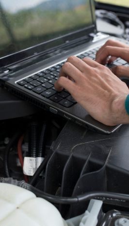 Una persona está escribiendo en una computadora portátil en un automóvil.