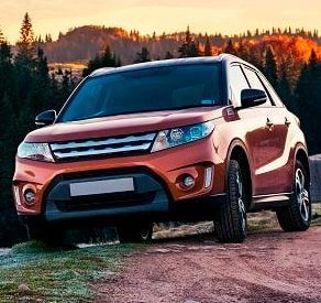 Una camioneta roja está estacionada al costado de un camino de tierra.