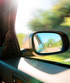 Un automóvil circula por una carretera y se ve el espejo retrovisor.