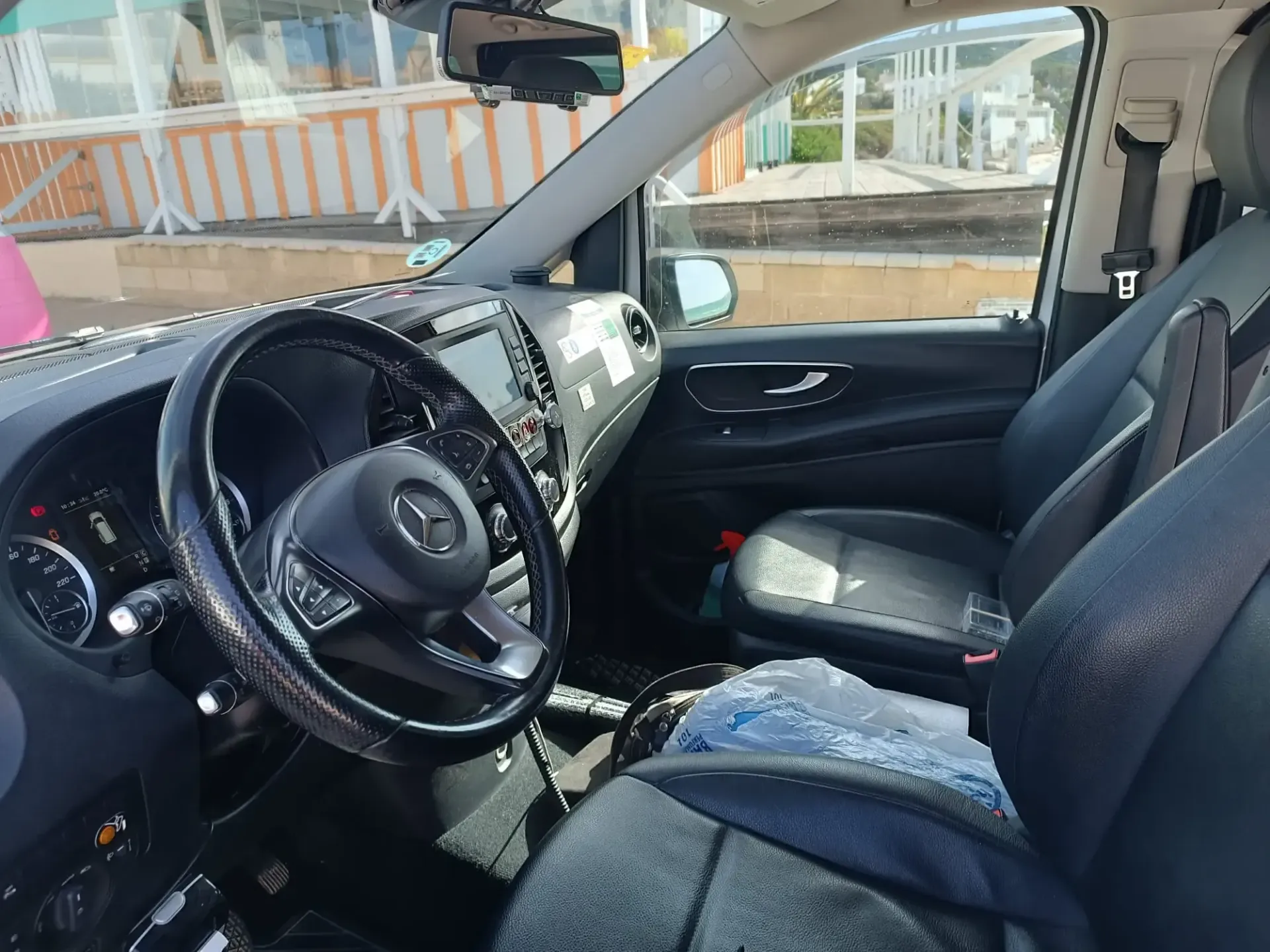 Interior de una furgoneta Mercedes-Benz negra. Se ven el asiento del conductor, el salpicadero, el volante y el asiento del copiloto.
